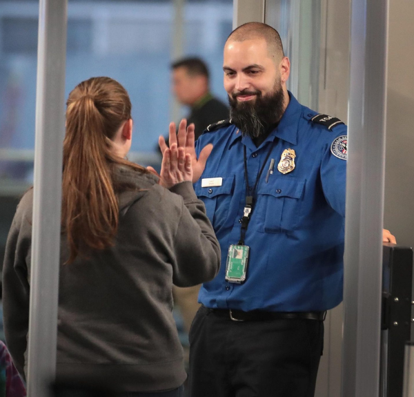 TSA officer enthusiastically high-fiving a passenger during a security checkpoint interaction.