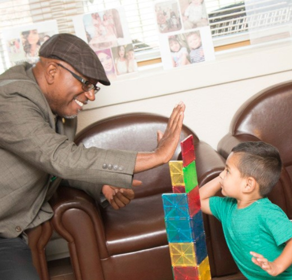 Office of Head Start, Regional Program Manager, Clarence Small high-fiving a young student.