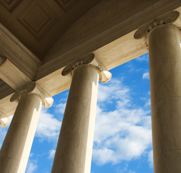 Pillars holding up a building with a blue sky in the background.