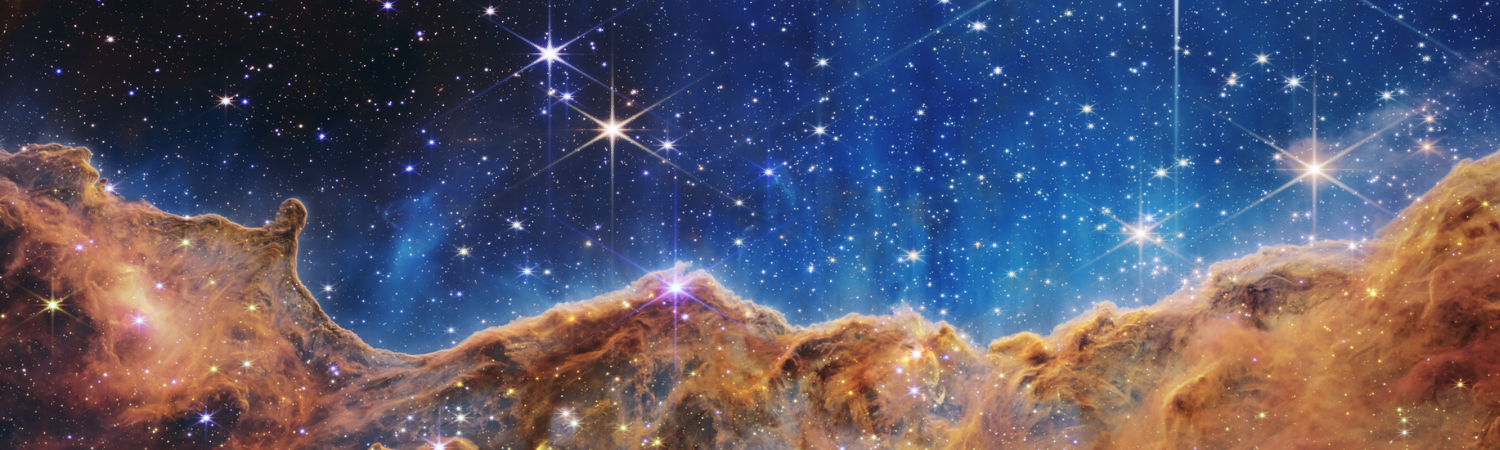 An undulating, translucent star-forming region in the Carina Nebula is shown in this Webb image, hued in ambers and blues; foreground stars with diffraction spikes can be seen, as can a speckling of background points of light through the cloudy nebula.