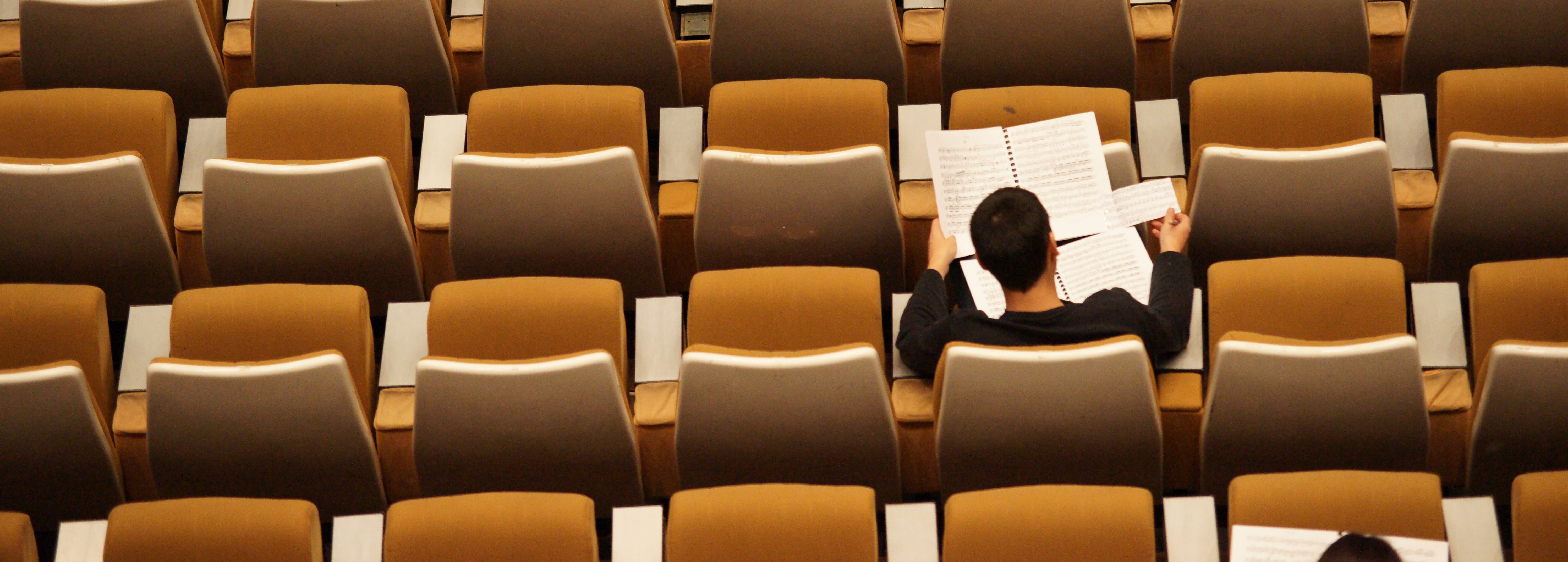 Student sitting in an otherwise empty lecture hall.