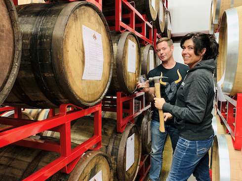 Jeff and Jennifer stand in front of barrels in their meadery.