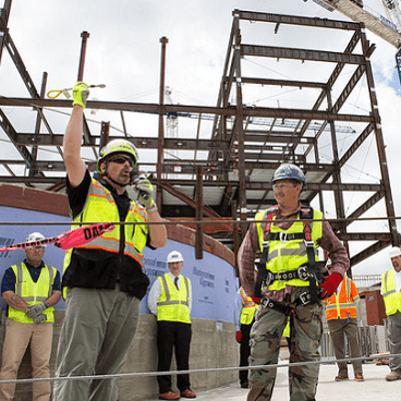 Four men in yellow construction vests assessing the state of a building that is in the progress of being built.