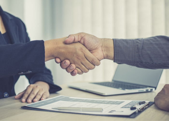 Two people shaking hands while in a job interview.